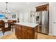 Kitchen island with wood cabinets, white countertop, and stainless steel refrigerator with view to dining area at 5305 Redfield Way, Cumming, GA 30028