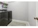 Neutral laundry room featuring sleek, dark gray washer and dryer set and functional shelving for organization at 5305 Redfield Way, Cumming, GA 30028