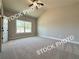 A light filled bedroom has neutral paint, carpet and trim, a ceiling fan, and a large window at 5720 Urban Village Way # 7, Tucker, GA 30084