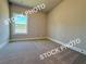 A bright bedroom with neutral carpeting and a large window at 5722 Urban Village Way # 8, Tucker, GA 30084