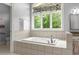 Bright bathroom featuring a soaking tub under a window and a tiled surround at 922 Pebblebrook Se Rd, Mableton, GA 30126