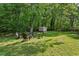 Green backyard with a fire pit, lawn, shed, and surrounded by lots of mature trees at 3344 Ridgecrest Dr, Powder Springs, GA 30127