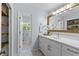 Bright bathroom with a white vanity, a wood-trimmed mirror, and a view to the exterior, featuring built-in shelves at 4842 Mcpherson Ne Dr, Roswell, GA 30075