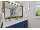 Bright bathroom featuring a double vanity with blue cabinets and a framed mirror at 4842 Mcpherson Ne Dr, Roswell, GA 30075