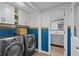 Well-organized laundry room with front loading washer and dryer and blue paneled accent wall and direct bathroom access at 4842 Mcpherson Ne Dr, Roswell, GA 30075