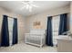 Bedroom featuring a white crib, dark blue curtains, and a ceiling fan at 4445 Ansley Ln, Cumming, GA 30040