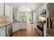 Open-concept kitchen features stainless appliances, light countertops, and hardwood floors, leading to outdoor patio at 4445 Ansley Ln, Cumming, GA 30040