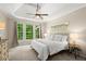 Comfortable main bedroom boasts a tray ceiling, ceiling fan, large windows, and neutral decor, offering a serene retreat at 4445 Ansley Ln, Cumming, GA 30040