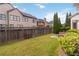 Landscaped backyard with mature trees, lush green lawn, and a wooden privacy fence at 663 Warm Springs Ct, Loganville, GA 30052