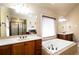 Elegant bathroom featuring a jetted tub, dual sinks, and a separate shower, providing a luxurious retreat at 663 Warm Springs Ct, Loganville, GA 30052
