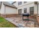 Tiled backyard patio area featuring brick accents, stainless steel gas grill, and landscaping at 663 Warm Springs Ct, Loganville, GA 30052
