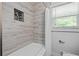 Bright bathroom featuring tub with modern gray tiling, shower niche, and window at 3153 Bonway Dr, Decatur, GA 30032