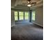 Carpeted main bedroom offers a tray ceiling, ceiling fan, and ample natural light from multiple windows at 4180 Cavalier Way, Duluth, GA 30097