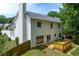 Rear exterior view of a two-story home with a wooden deck, fenced yard, and mature trees at 4613 Creek Forest Ct, Lilburn, GA 30047
