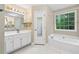 Bright bathroom features a white vanity, soaking tub, and a window with a view of the trees at 4613 Creek Forest Ct, Lilburn, GA 30047