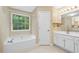 Bright bathroom with a white vanity, soaking tub, and a window view at 4613 Creek Forest Ct, Lilburn, GA 30047