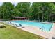 Large community pool with plenty of lounge chairs and shaded picnic area surrounded by trees at 4613 Creek Forest Ct, Lilburn, GA 30047