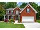 Beautiful brick home with a covered porch, lush landscaping, and attached two-car garage at 4613 Creek Forest Ct, Lilburn, GA 30047