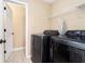 Laundry room featuring shelving, tile flooring, and modern black washing and drying machines at 5427 Highway 81, Loganville, GA 30052