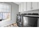 Convenient laundry room features modern washer and dryer, storage cabinets, and a bright window at 6119 Fairlong Nw Run, Acworth, GA 30101