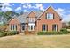 Charming brick home with a manicured front lawn, mature landscaping and black shutters on the windows at 13090 Magnolia Crescent Dr, Roswell, GA 30075
