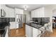 Modern kitchen with white cabinetry, stainless steel appliances, black countertops, and sleek bar stools at 13090 Magnolia Crescent Dr, Roswell, GA 30075