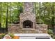 Relax by the outdoor fireplace, surrounded by lush greenery and landscape at 4052 Loch Highland Ne Pass, Roswell, GA 30075