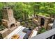Aerial view of a stone patio area with fireplace and outdoor seating in a private wooded backyard at 4052 Loch Highland Ne Pass, Roswell, GA 30075