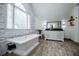 A bright bathroom featuring a luxurious soaking tub, vanity, and large window with abundant natural light at 213 Shady Valley Dr, Carrollton, GA 30116