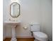 Charming pedestal sink with an octagon mirror, paired with a standard toilet and hardwood flooring at 213 Shady Valley Dr, Carrollton, GA 30116