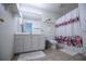 Bright bathroom with floral shower curtain, vanity with shelves and neutral tile floor at 213 Shady Valley Dr, Carrollton, GA 30116