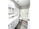 Bright bathroom featuring modern white vanity, tub with shower, and stylish gray wood-look flooring at 6945 Autumn Hills Dr, Cumming, GA 30028