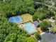 An eye-level aerial view showing tennis courts, a pool, and the surrounding lush greenery at 3524 Old Towne Ln, Cumming, GA 30040