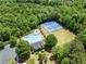 A lovely aerial view showcases the pool, tennis courts, and surrounding verdant forest at 3524 Old Towne Ln, Cumming, GA 30040