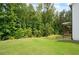 A well-manicured lawn sits adjacent to a lush forest with a covered porch visible on the house at 63 Brookstone E Park, Acworth, GA 30101