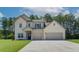 Lovely two-story home boasts a light brick exterior, covered porch, and a spacious two-car garage at 211 Linford Dr, Locust Grove, GA 30248