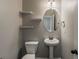 Half bathroom features a pedestal sink, a toilet, and an oval mirror with floating shelves at 5567 Union Pointe Pl, Union City, GA 30291