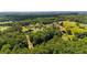 Wide aerial view of the home in a vibrant, green, heavily wooded area, showcasing the area's expansive acreage at 104 Meadow View Trl, Canton, GA 30115
