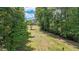 The backyard features a clear grassy path that slopes uphill with trees outlining the perimeter of the lawn at 104 Meadow View Trl, Canton, GA 30115