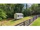 Outbuilding in the backyard alongside a black perimeter fence surrounded by mature trees at 104 Meadow View Trl, Canton, GA 30115