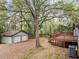 View of a detached garage and stairs leading up to a wooden deck surrounded by lush greenery and mature trees at 2205 Stockbridge Se Dr, Atlanta, GA 30316