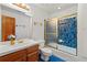 Bathroom with blue tile accent and wood-trimmed vanity and golden shower door at 1019 Henna Se Ct, Conyers, GA 30013