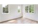 Sunlit bedroom with hardwood floors and three windows showing lush greenery outside at 1211 Reeder Ne Cir, Atlanta, GA 30306