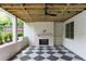 Inviting outdoor living space featuring a fireplace, ceiling fan, and a stylish black and white checkered floor at 1211 Reeder Ne Cir, Atlanta, GA 30306