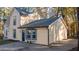 Two-story home with a driveway, tan siding and black trim and windows surrounded by trees at 7156 Whitfield Dr, Riverdale, GA 30296