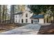 Two-story home with a concrete driveway, tan siding and black trim and windows surrounded by trees at 7156 Whitfield Dr, Riverdale, GA 30296