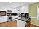 Well-lit kitchen with white cabinets, stainless steel appliances, and a breakfast bar on hardwood floors at 1192 Pathfinder Rd, Marietta, GA 30066