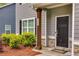 Home's front entrance with dark door, wood support beam, stone accents, landscaping, and visible house number at 209 Shelton Cir, Temple, GA 30179