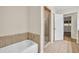 Bathroom with tiled shower, white tub, and tile floors leading to bedroom at 2288 Hudson Sw Dr, Lilburn, GA 30047