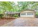 Charming home featuring an attached two-car garage and lush landscaping, set back from a long driveway, surrounded by mature trees at 2288 Hudson Sw Dr, Lilburn, GA 30047